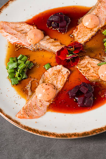 Smoked salmon sashimi plated with beetroot, scallions, and spicy sauce