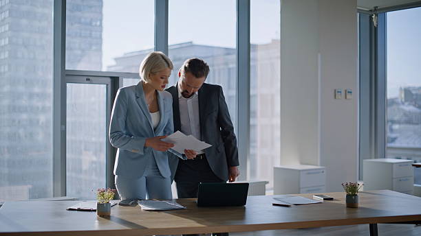 istock Business couple checking documents in panoramic office. Busy coworkers calling 2235376120