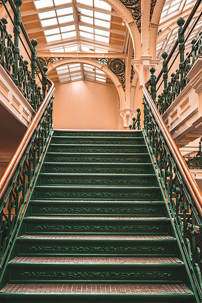 istock Elegant green staircase ascending under ornate skylight in victorian building 2235384192