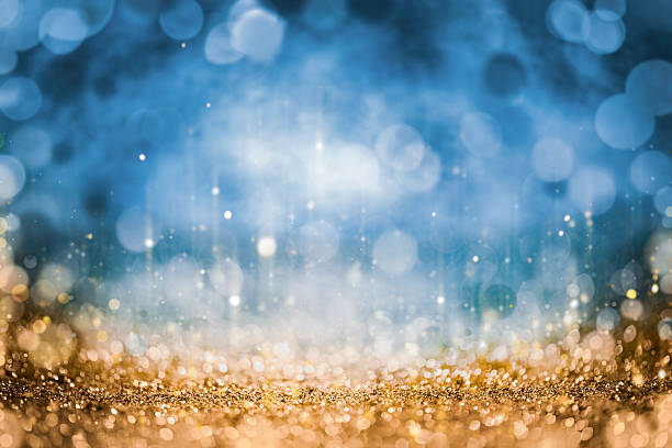 Abstract sparkling background with golden glitter in the foreground and blue bokeh lights in the background. Festive and elegant atmosphere, ideal for celebrations, luxury concepts and holiday designs.