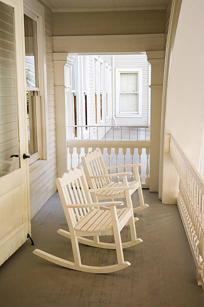 Two wooden rocking chairs sitting on the porch of a log cabin