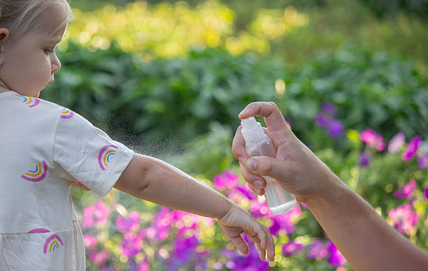 istock Father applying insect repellent spray to child's hand outdoors. Selective focus 2235388836