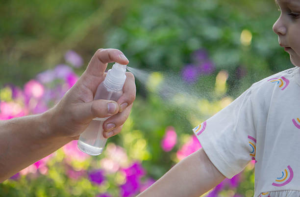 istock Father applying insect repellent spray to child's hand outdoors. Selective focus 2235388837