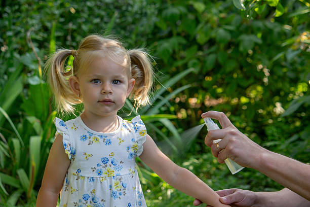 istock Father applying insect repellent spray to child's hand outdoors. Selective focus 2235388844