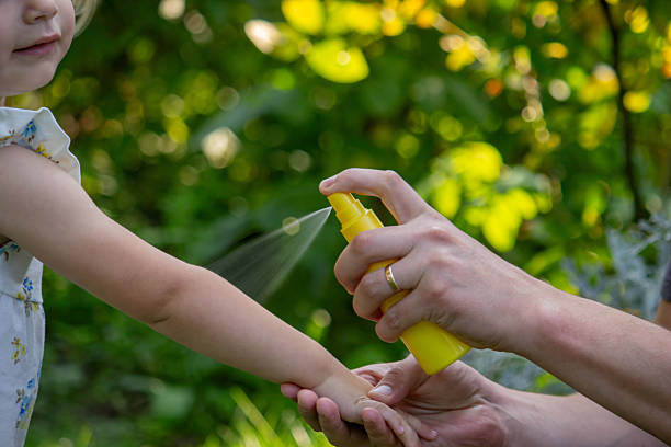 istock Father applying insect repellent spray to child's hand outdoors. Selective focus 2235388848