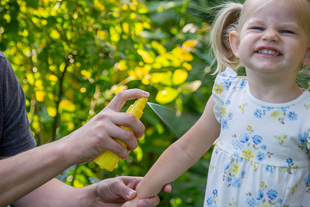 istock Father applying insect repellent spray to child's hand outdoors. Selective focus 2235388849
