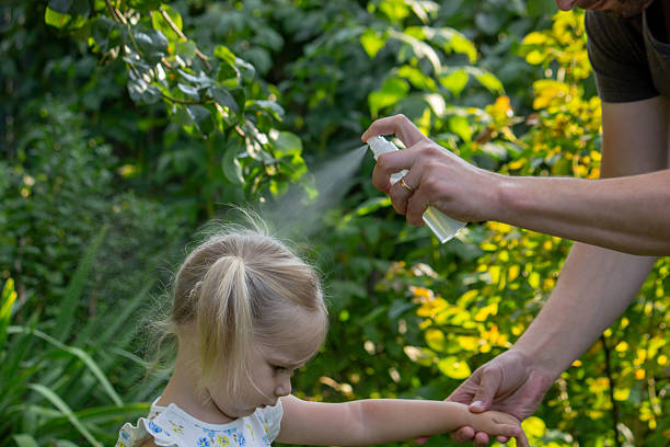 istock Father applying insect repellent spray to child's hand outdoors. Selective focus 2235388872