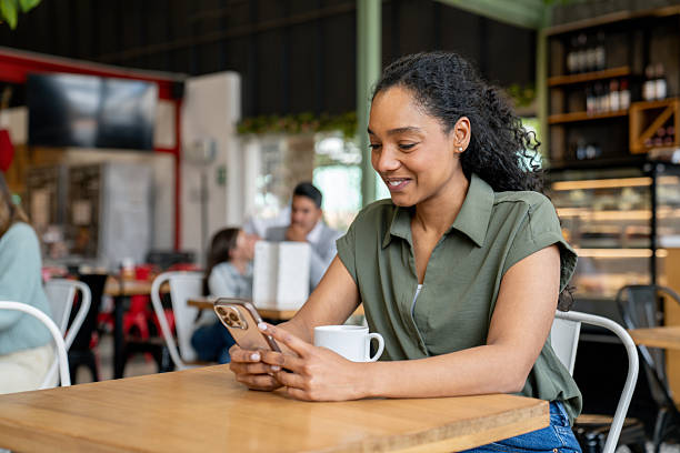 istock Happy woman drinking coffee at a cafe while texting on her cell phone 2235389234