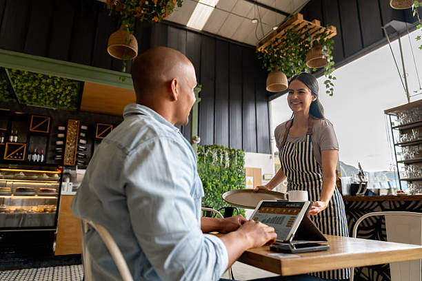 istock Happy waitress serving a drink  to a man working at a cafe 2235389235