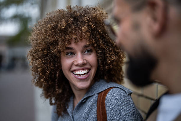 Cheerful young woman with curly hair is engaging in a friendly conversation with a man, her genuine smile radiating warmth and positivity