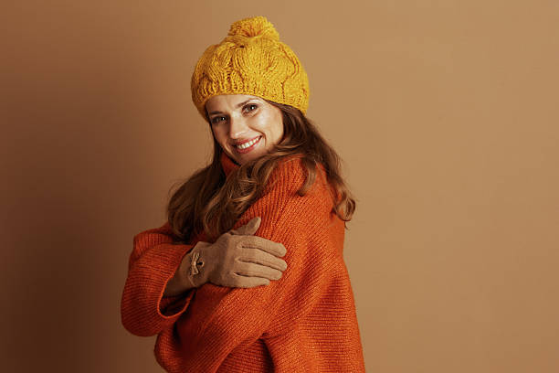 istock Smiling Woman in Oversized Orange Sweater & Beanie 2235391444