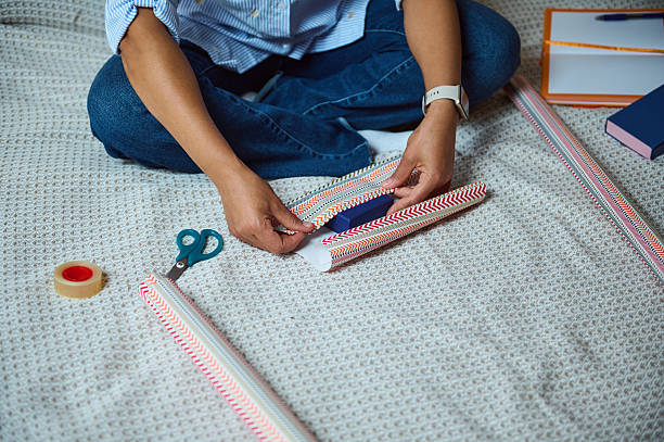 istock Person Wrapping A Gift Using Decorative Paper and Tape on a Bed 2235396287
