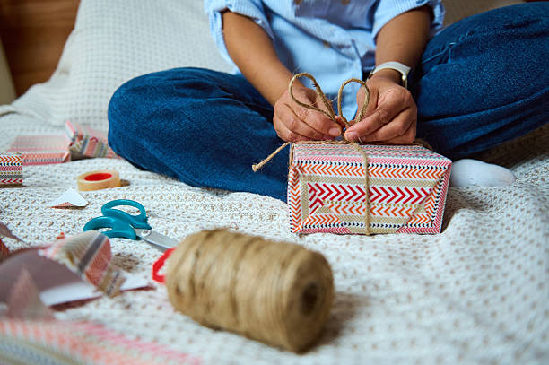 istock Person Wrapping Colorful Gift Box with String on a Cozy Surface 2235396337