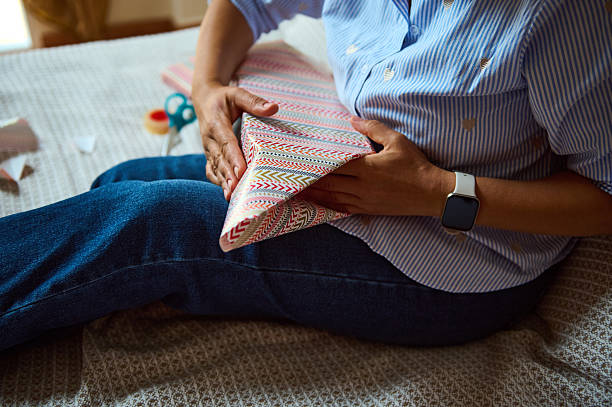 istock Person Wrapping Gift with Decorative Paper on a Comfortable Surface 2235396348