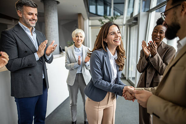istock Businesswoman shaking hands while receiving congratulations from colleagues 2235398959