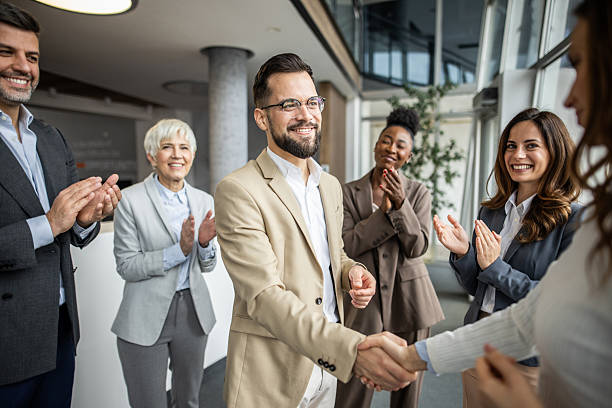 istock Businessman shaking hands while receiving congratulations from colleagues 2235401490