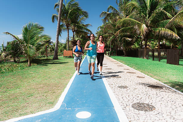 group of three young woman running on fitness track along the beach