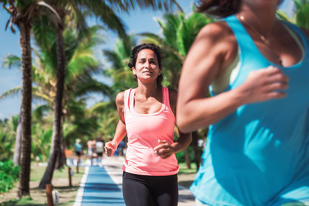 young woman running on fitness track along the beach in the sun