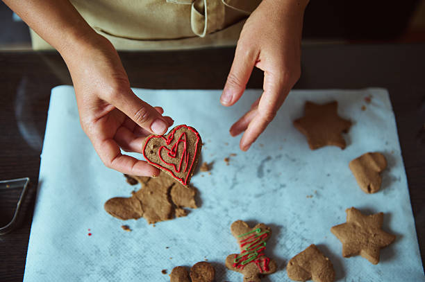 Close-Up of Hands Decorating Homemade Gingerbread Cookies on Baking Paper