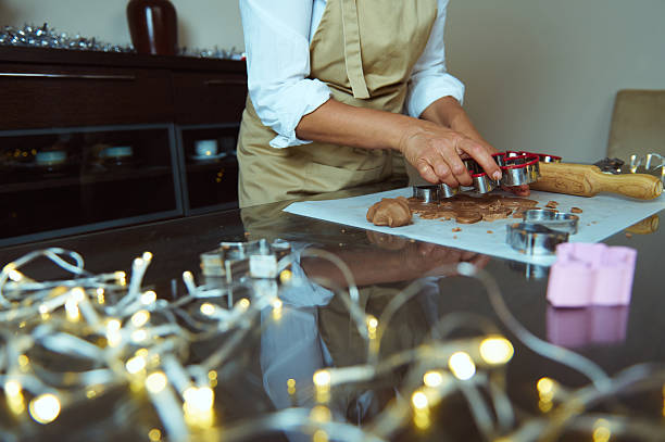 istock Person Baking Gingerbread Cookies with Decorative Lights in Festive Kitchen Setting 2235404966