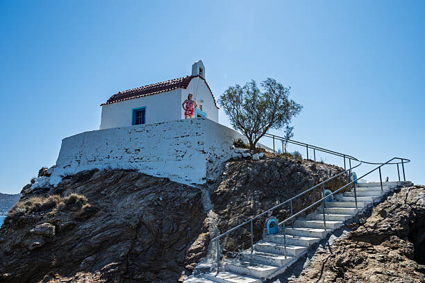 Low angle view of woman exploring old chapel on hill, Church of Agios Isidoros, Leros, Greek Islands