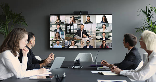 istock Group of diverse businesspeople gathered in boardroom engaging in videoconference 2235407940