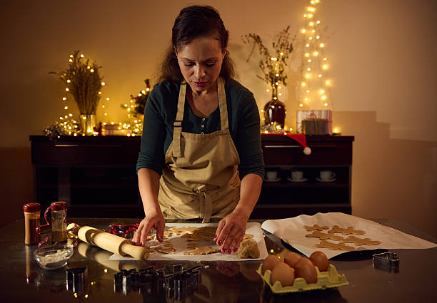 istock Woman Baking Gingerbread Cookies Surrounded by Christmas Decorations and Warm Lighting 2235409900