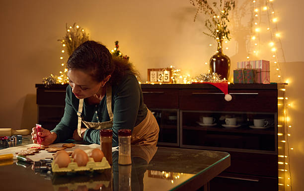 istock Woman Decorating Festive Gingerbread Cookies in Warm Christmas Kitchen Setting 2235410130