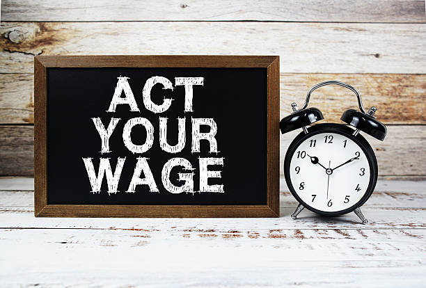 istock Act Your Wage text message and alarm clock on wooden background 2235411134