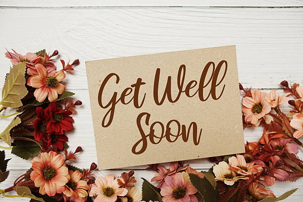 istock Get well Soon typography text with flower decorated on wooden background 2235411286