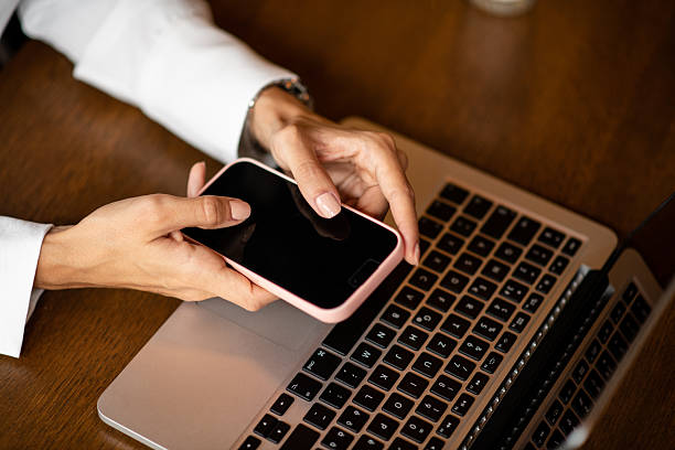 istock Woman holding phone during work on laptop 2235412881
