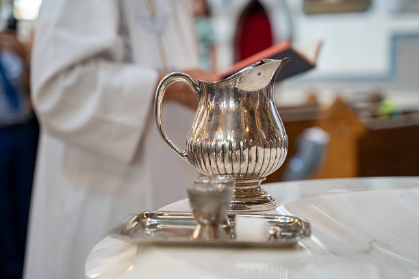 Silver baptism pitcher and chalice on church altar.