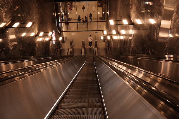 Automatic escalator stairways at the underground metro station, group of people who got down by the stairs, modern city life, public transportation in big city