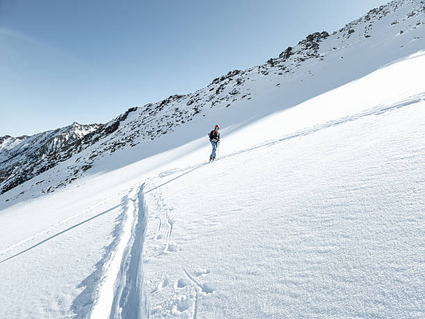 istock Single female ski tourer ascending in fresh snow 2235417207