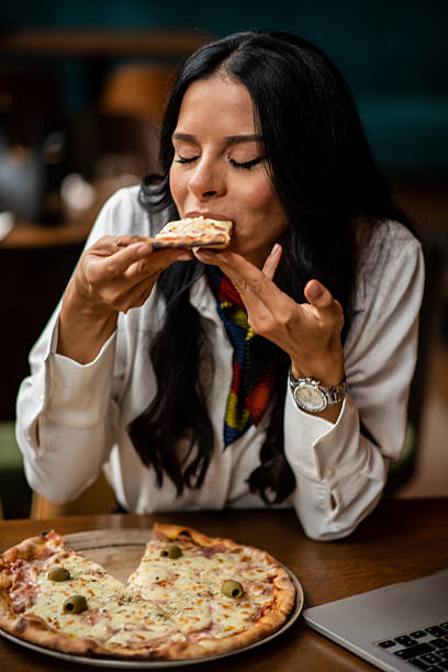 istock Woman eating pizza slice in restaurant 2235421745