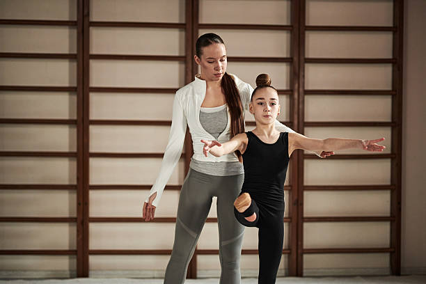 istock Caucasian Woman Instructing Young Girl Practicing Ballet Posing 2235424239