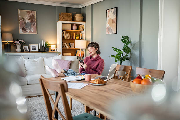 istock Young woman relaxing on the dining table while using smartphone at home 2235424243
