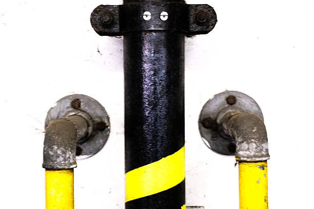 London UK, September 14 2025,  Vertical Iron Pipework Fixed To A Buildings Interior Wall Painted Yellow And Black