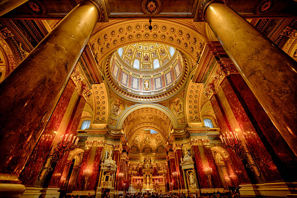 Budapest, Hungary - July 28, 2025: Interior views of St. Stephen’s Basilica showcase the richly decorated dome, marble columns, gilded ornamentation, and neoclassical design.