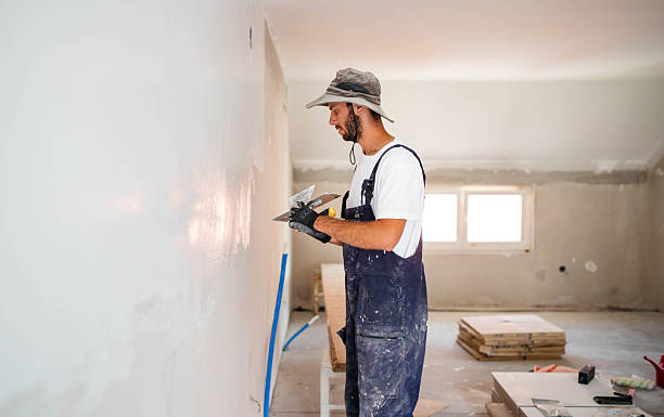 istock Plasterer man at work with trowel plastering the wall 2235436396