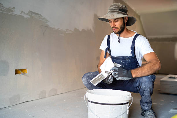 istock Plasterer man at work with trowel plastering the wall 2235436493