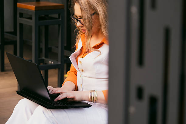 istock Successful business woman working outdoors on a laptop while engaged in a conversation on her phone 2235439877