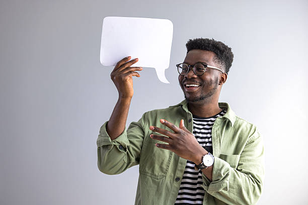 istock Smiling Man Holding Speech Bubble Sign in Casual Attire 2235445405