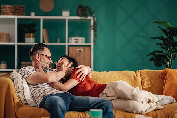 istock Happy couple embracing and laughing on sofa at home 2235445702