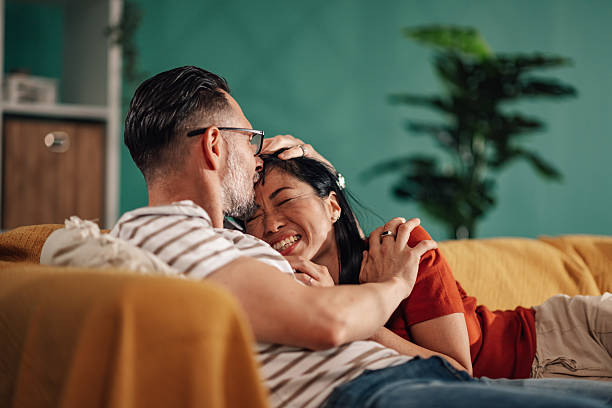 istock Happy couple relaxing and embracing on sofa at home 2235445711