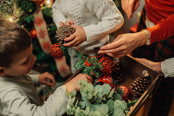 istock Family decorating christmas tree with ornaments and pine cones 2235446171