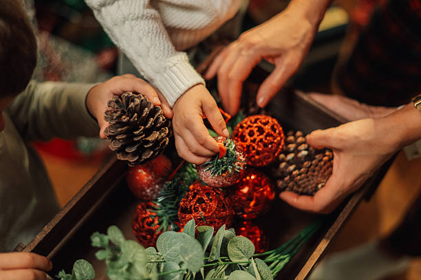 istock Family decorating for christmas using pine cones and red ornaments 2235446173