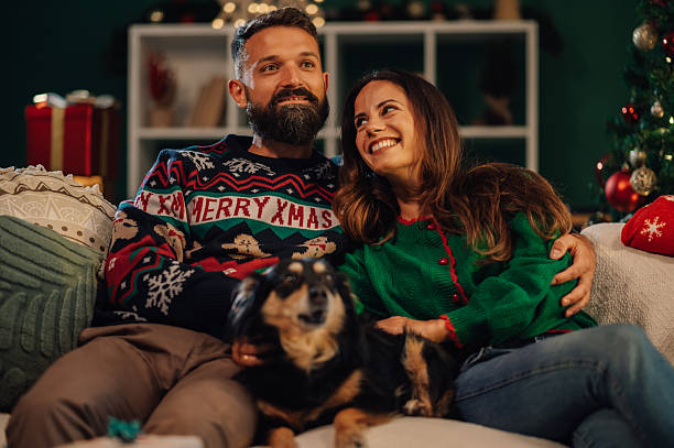 istock Couple wearing christmas sweaters relaxing on sofa with their dog 2235446954