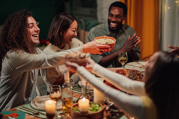 Friends passing food at thanksgiving dinner table
