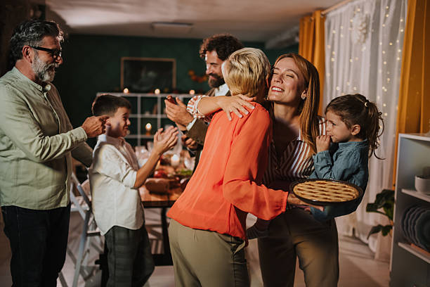 Family celebrating thanksgiving, hugging and bringing pie
